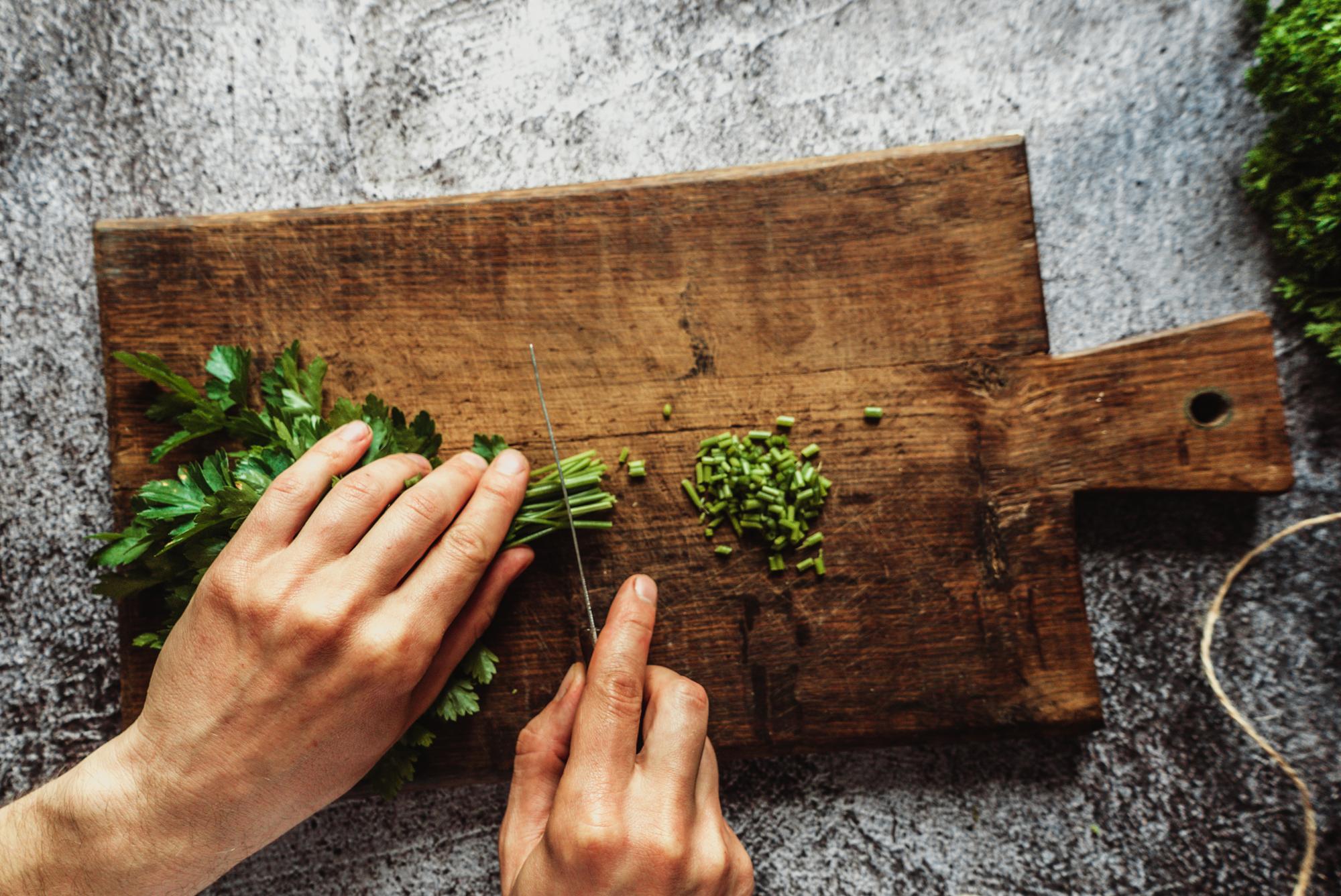 Chef che affetta erbe fresche in cucina artigianale